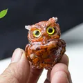 Miniature owl figurine with red crystal resin stones and yellow eyes held in hand - Red Jasper