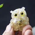 Miniature resin owl figurine with embedded natural crystals and yellow eyes - Rutilated Quartz