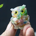 Resin owl figurine with natural crystals held between fingers showing its small size - Colorful Cat Eye