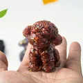 Miniature reddish-brown resin teddy dog figurine with gold leaf accents held in hand - Red Jasper
