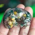 Sleeping dragon resin figurine filled with colorful natural crystal stones on palm - Ocean Jasper