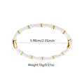 Detailed view of bamboo style bangle with white resin and gold plated metal beads - White