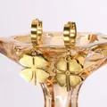 Golden stainless steel four-leaf clover hoop earrings on amber glass display - Four-leaf Clover / Gold