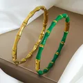 Detail view of bamboo joint bracelets in gold and green enamel on silk fabric - Gold and Green