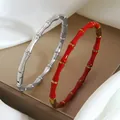 Détail de bracelets en forme de bambou en argent poli et rouge doré sur de la soie - Argent et Rouge