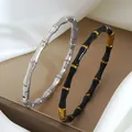 Vue détaillée de joncs bambou en argent et noir avec fermoir magnétique sur de la soie - Argent et Noir