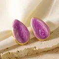 Dettaglio macro di orecchini a goccia dorati con smalto marmorizzato viola su seta - Viola