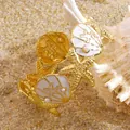 Detailed shot of starfish and shell cuff bracelet with enamel on a sandy beach - White