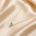 Close-up of golden heart necklace with light blue gemstone on silky champagne fabric - Blue