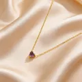 Detail eines lila Herz-Anhängers an einer Goldkette auf champagnerfarbener Seide - Lila