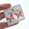 Detailed macro view of pink marble texture butterfly earrings with gold-plated stainless steel edges - Butterfly Stud Earrings (FYD6102EH)