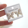 Detail of golden butterfly stud earrings with white marble texture on a display card - Butterfly Earrings (FYD6102EH)
