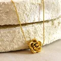 Golden rose pendant necklace and earrings set on natural stone background display - Flower Necklace / Gold