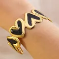 Gold-plated C-shaped stainless steel cuff bracelet with black enamel heart accents - Black