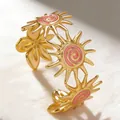Golden sun-shaped cuff bracelet with pink enamel spiral design and floral accents - Light Pink