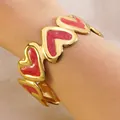 Golden C-shaped stainless steel cuff bracelet with vibrant red enamel heart patterns - Red