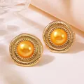 Close-up of vintage gold round button earrings with sunburst texture and orange pearl inlay - Gold Base With Orange Faux Pearl