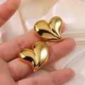Mirror polished gold heart earrings with irregular 3D shape held against silk fabric - Gold