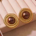 Macro shot of vintage round gold-plated stud earrings with brown pearlescent inlay - Gold Base With Brown Faux Pearl
