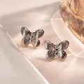 Detailed view of silver butterfly stud earrings with fine textured wings on white silk - Butterfly Style (FYD6085-1)