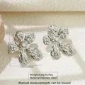 Detail of silver stainless steel flower earrings with liquid metal texture on stone surface - Liquid Metal Flower (FYD6177-1)