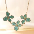 Elegante goldene Blumenhalskette mit hellblauen Marmoremaille-Blütenblättern für Damen - Blaue Halskette