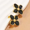 Dettaglio di orecchini a fiore con petali in smalto nero e centro dorato a nido d'ape - Orecchini a Bottone (FYD6111-black) / Nero