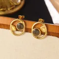 Orecchini tondi d'oro con pietre occhio di gatto grigie e gialle su uno sfondo vintage - Orecchini a Cerchio Occhio di Gatto Bicolore (FYD6071EH-black)