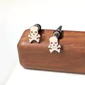 Pendientes de calavera de acero inoxidable pulido sobre soporte de madera - Estilo de Cuerpo de Esqueleto Completo