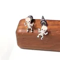 Detalle de pendientes de calavera de acero inoxidable sobre una base de madera oscura - Estilo de Cráneo Plano con Cuencas Grandes