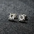 Primer plano de pendientes de sol en plata pulida con bordes de llama sobre negro - Girasol