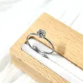 Primer plano de un anillo floral ajustable de plata con una flor delicada en soporte madera - Estilo Rosa (Color Acero)