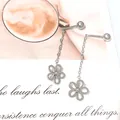 Primer plano de aretes de flores de plata mate con borlas sobre un fondo decorativo - Borla de Flor Calada / Un par / Color acero