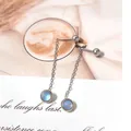 Close-up of minimalist silver tassel earrings with blue gemstone on magazine background - Steel-Frosted Moonstone Tassel