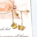 Detalle de elegantes pendientes de mariposa dorada con borlas sobre tarjeta blanca - Color Dorado 2 en 1 Mariposa Esmerilada Borla