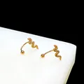 Detailed view of golden snake-shaped stud earrings with textured scales on a white block - Snake U-Shape / Gold