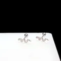 Detailed close-up of snake-shaped silver steel ear studs with textured scales and screw ball back - Snake Cartilage Stud / Silver