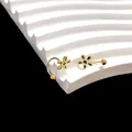 Close-up van gouden madeliefje oorbellen met zwart email op een gegolfde display - Gouden Bloem