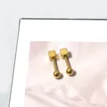 Macro-opname van geometrische gouden kubusoorbellen met ronde bolsluiting en glanslak - Vierkante Draai Bal Stijl / Goud