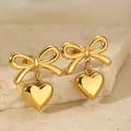 Dettaglio macro di orecchini dorati con fiocco e cuore su superficie in pietra - Solo Orecchini / Oro