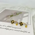 Makroaufnahme der goldenen Kleeblatt-Ohrstecker mit schwarzer Emaille und Schraubverschluss - Schwarzes Kleeblatt U-Form Stil