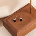 Detail of silver round stud earrings with black enamel inlay on dark wood surface - Round Shape
