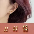 Drie maten gouden titanium stalen dubbele bol oorbellen getoond in een lifestyle-shot - 3mm Goud Dubbele Bal