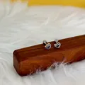 Detalle de pendientes de corazón con líneas concéntricas negras y cierres de rosca - Mano sosteniendo corazón / Color acero