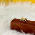 Detalle macro de pendientes de corazón dorados con esmalte negro en base de madera - Corazón / Dorado