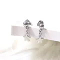 Close-up of titanium steel ball earrings with hollow star pendants on white display - Pentagram