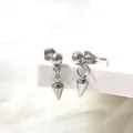 Macro shot of silver titanium steel ball stud earrings with punk style cone spike pendants - Cone