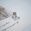Détail de boucles d'oreilles en cœur ajouré avec fermoir à vis sécurisé sur carte - Style Coeur Creux Argenté