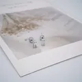 Vue détaillée de boucles d'oreilles fantômes en argent avec fermoir à vis sur carte - Style Fantôme Argent