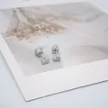 Vue détaillée de boucles d'oreilles cœur en argent avec fermoir à vis sur carte fleurie - Style Coeur Argent